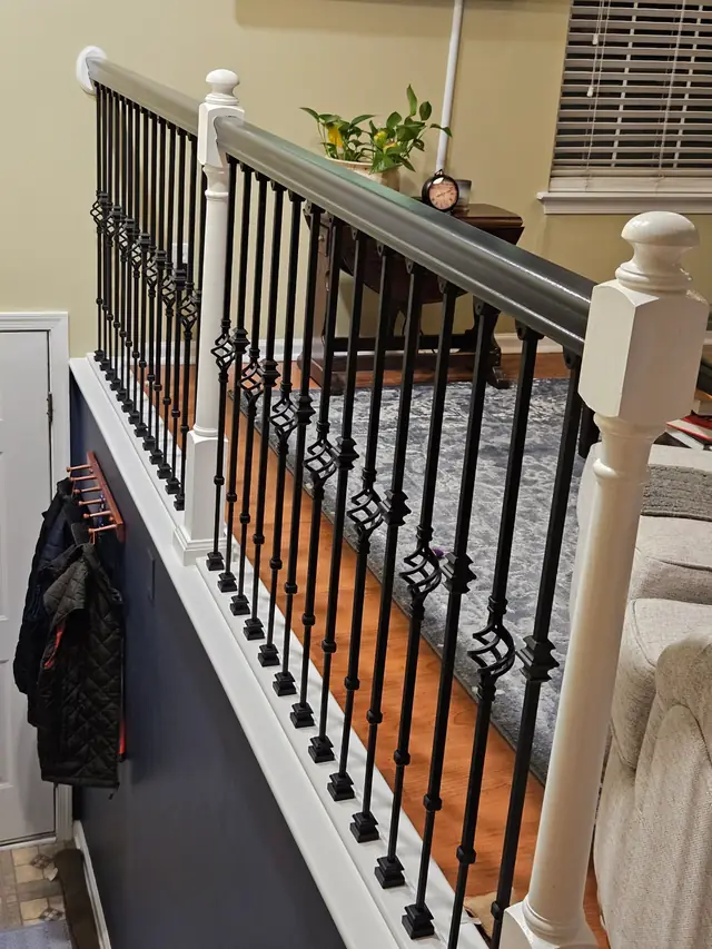 Black basket balusters and a white newel post on a new loft stair railing over an oak floor