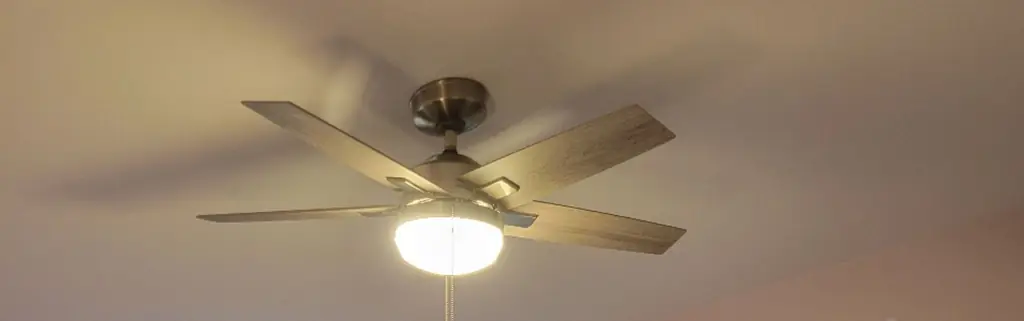 A new five-blade ceiling fan with a glass light kit in a freshly painted bedroom