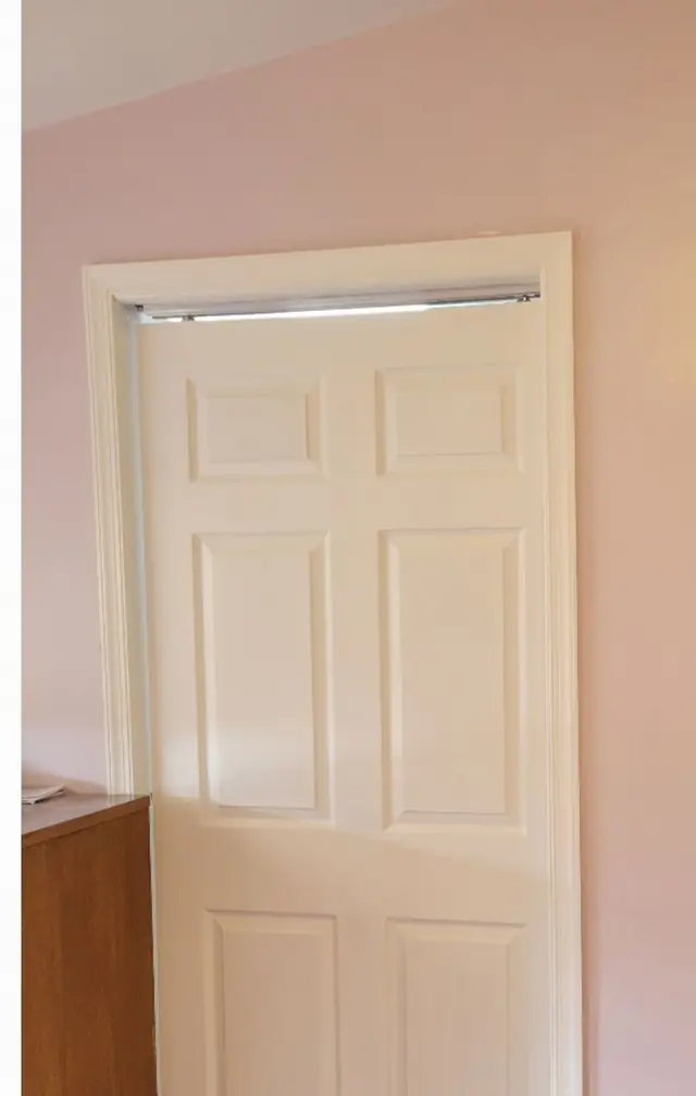 A white six-panel pocket door set into a pink wall with a clean white casing