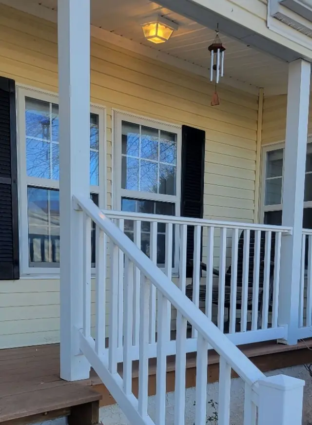 A rebuilt white porch railing and stair rail on a yellow-sided house